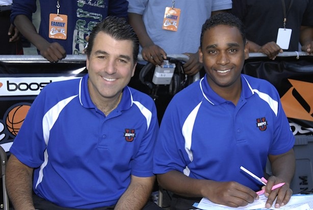 Dwayne Ballen and his announcing colleague in blue ESPNU shirts at a courtside broadcast desk