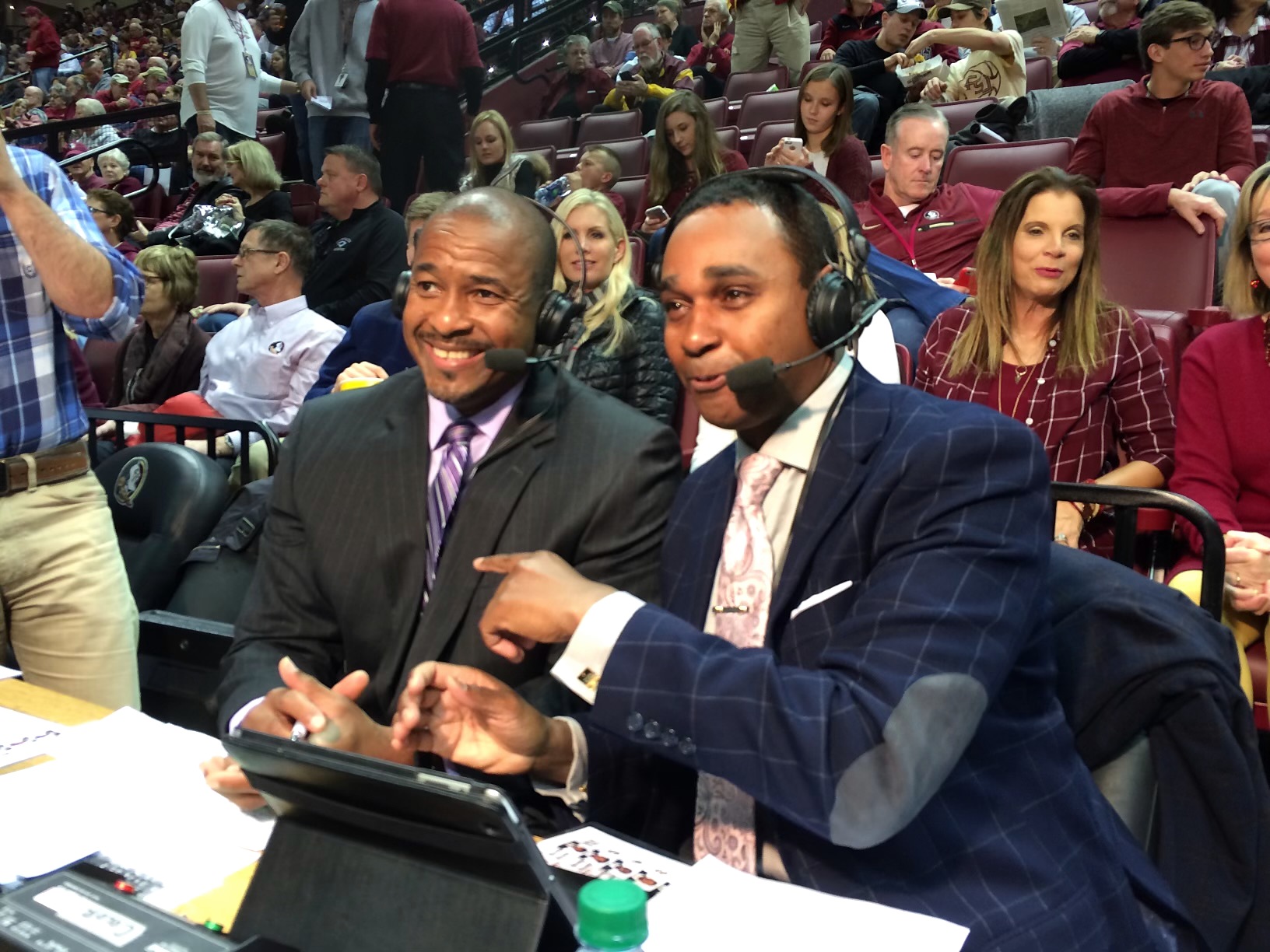 Dwayne Ballen wearing a broadcast headset beside his announcing colleague at a courtside commentary desk