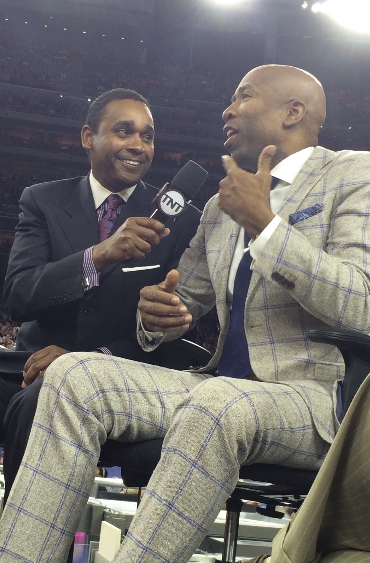 Dwayne Ballen holding a TNT microphone up to Kenny Smith during a Final Four broadcast