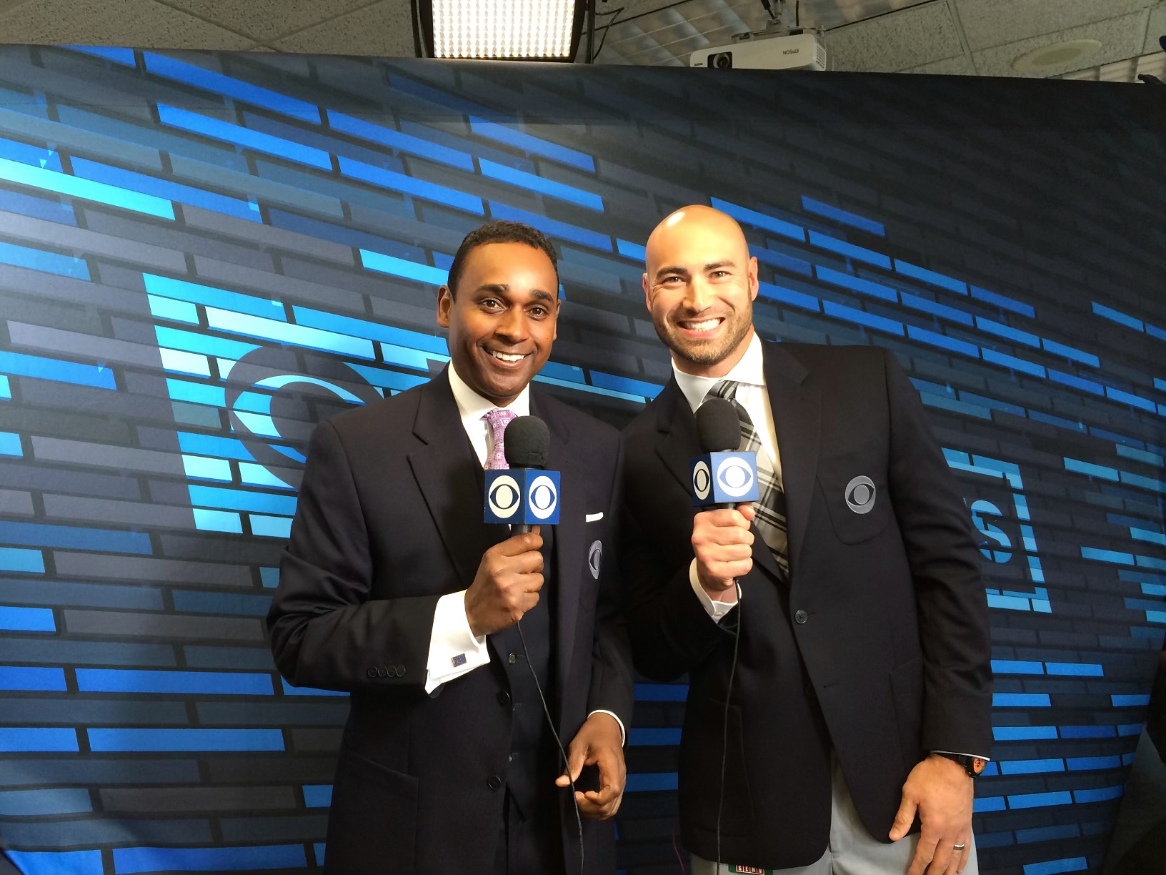 Dwayne Ballen and a broadcast colleague holding CBS microphones in front of a blue broadcast backdrop