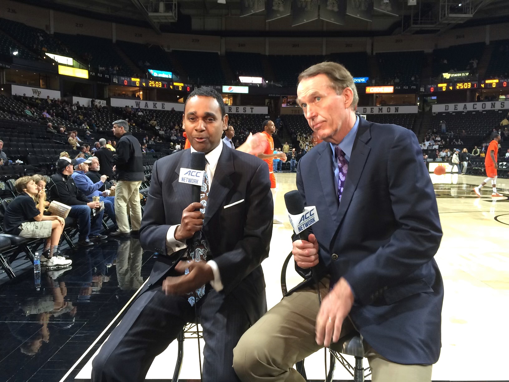 Dwayne Ballen and his broadcast partner holding ACC Network microphones courtside at Wake Forest