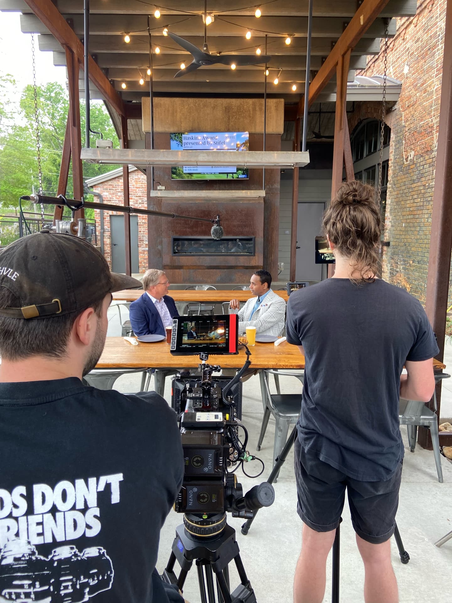 A film crew rolling a cinema camera and boom microphone on a table interview between Dwayne Ballen and a guest